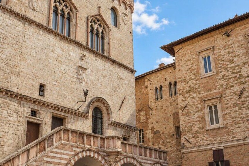 A stone building with arched windows and a staircase leading to a door. 4