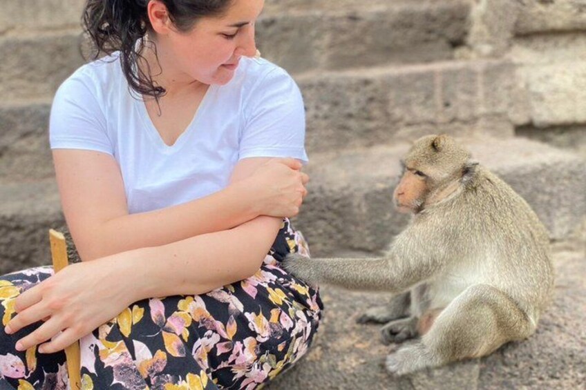 A person sitting on steps with a monkey on their lap. 1