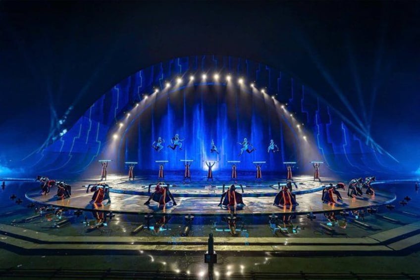 A stage with performers in red and blue costumes, a large arch structure, and spotlights. 5