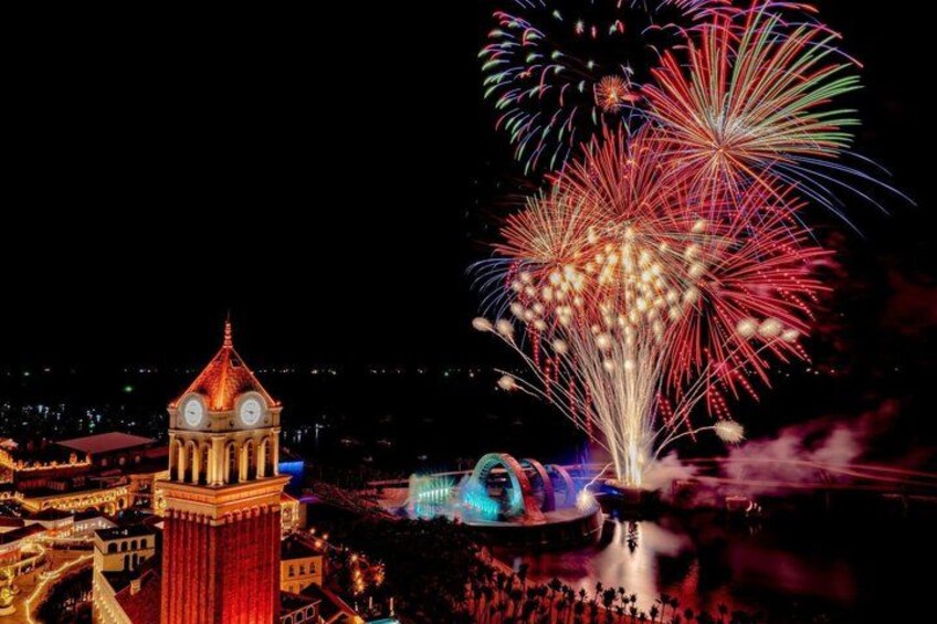 A clock tower, fireworks, and a cityscape at night. 1
