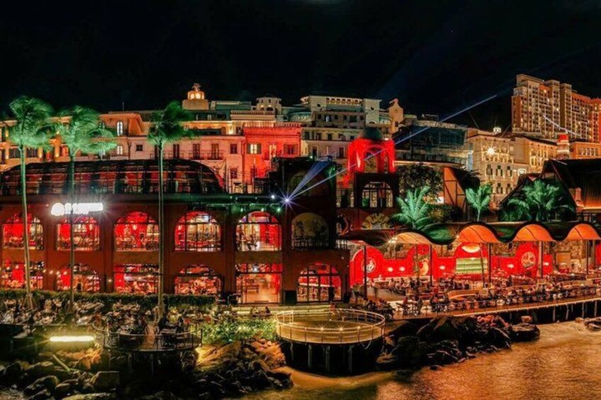 A waterfront restaurant with outdoor seating, palm trees, and a water feature. 2