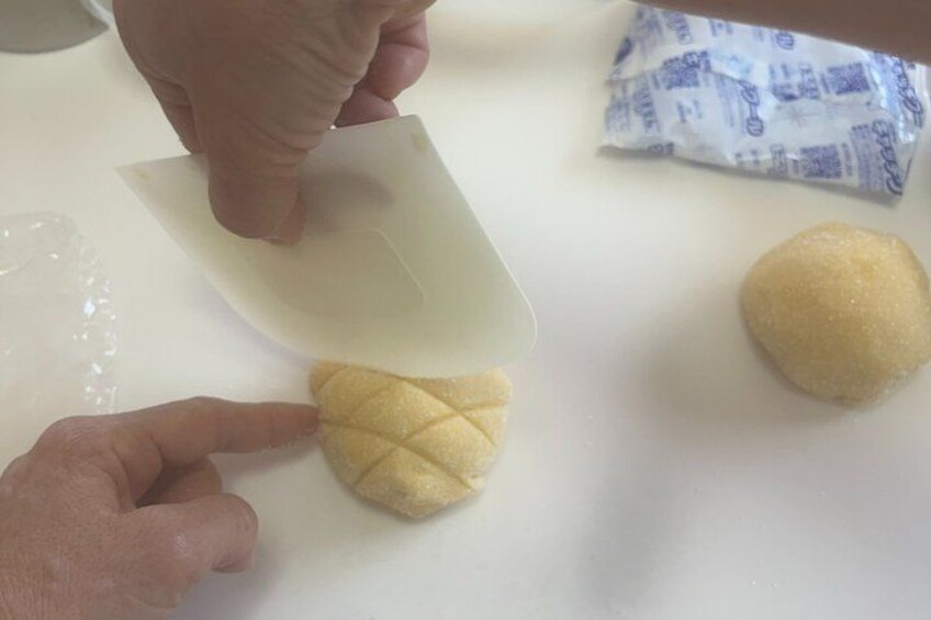 A person cutting a piece of dough with a knife on a white surface. 5