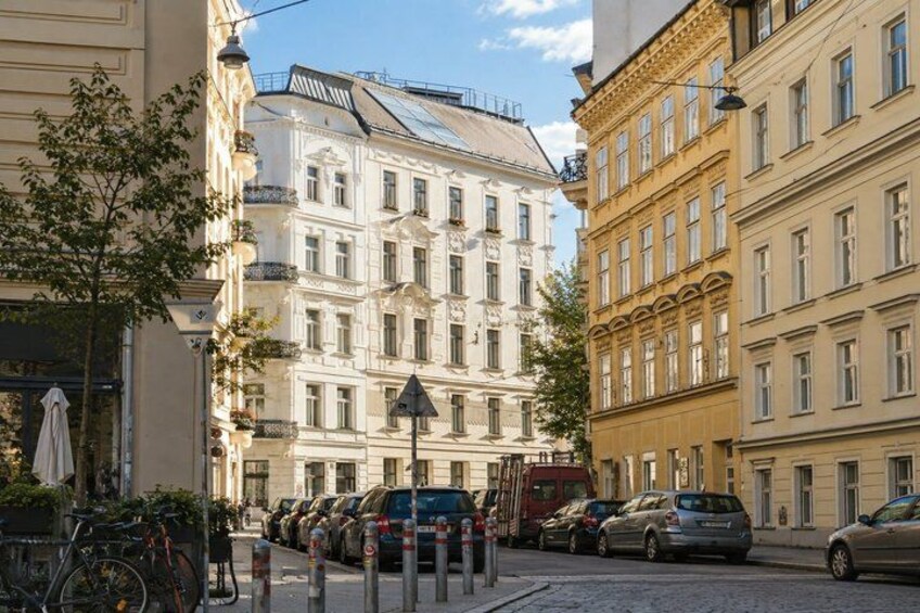 A street with parked cars, a bicycle, and classic European architecture. 5