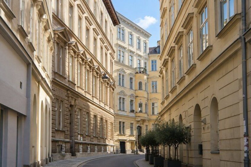 A street with classical architecture, a central building with a grand entrance, and a tree-lined sidewalk. 3