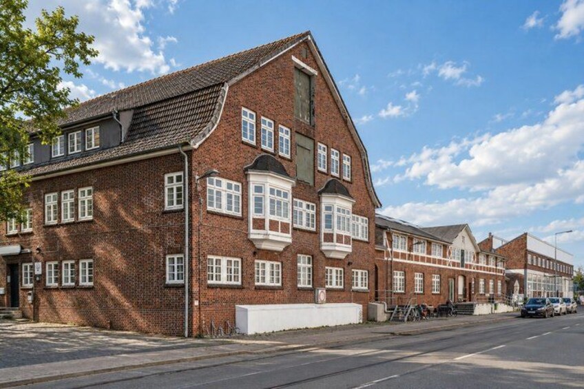A red brick building with multiple windows and a sloped roof. 4