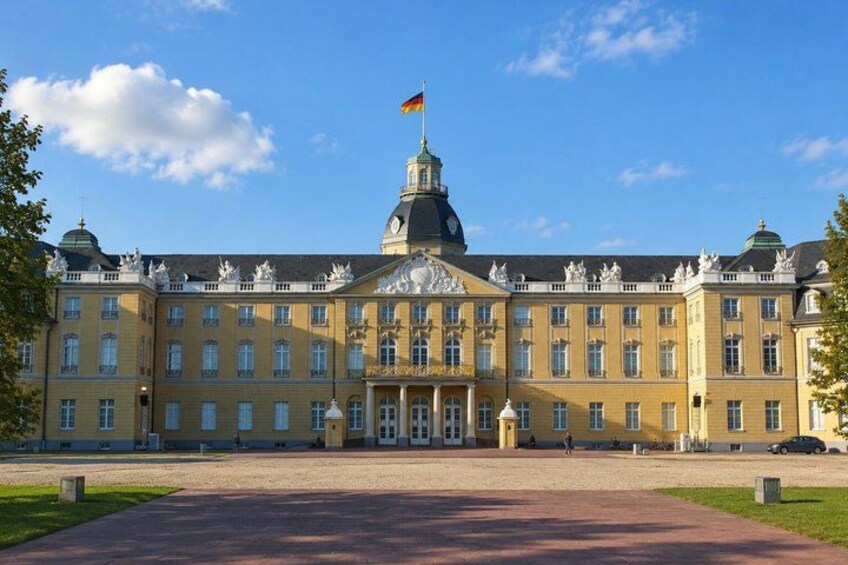 A large, historic building with a prominent flag, a central dome, and symmetrical architecture. 2