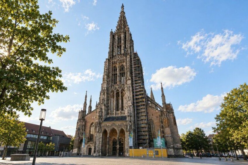 A Gothic cathedral with a tall spire, scaffolding, and a clear blue sky. 2