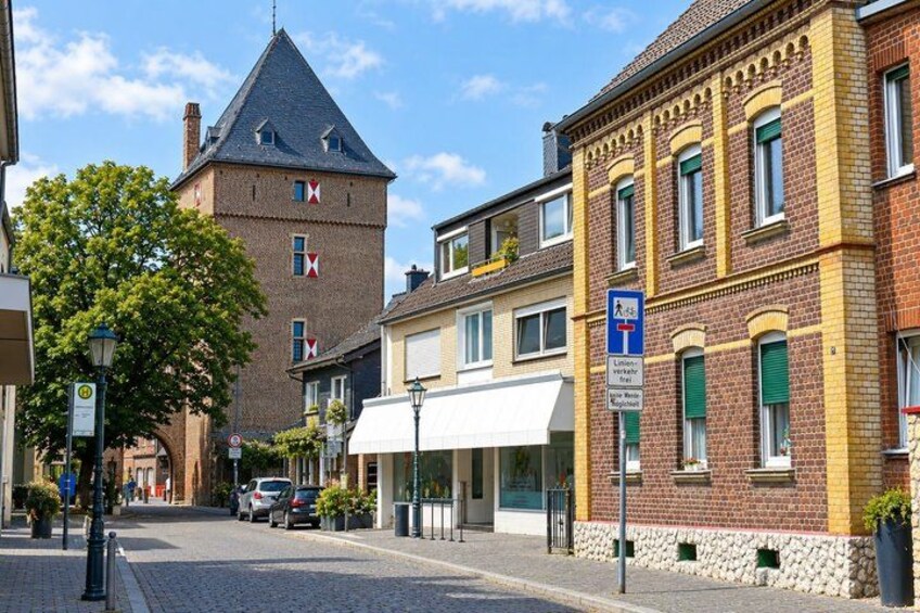 A cobblestone street with historic buildings, a tower, and a pedestrian crossing sign. 5