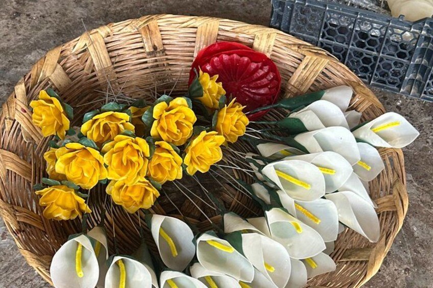 A wicker basket with yellow and white flowers, a red object, and a blue plastic crate. 1