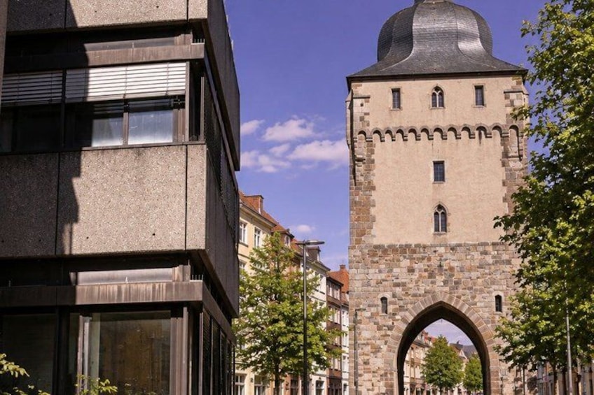 A modern building and a historic tower with an arched entrance. 2