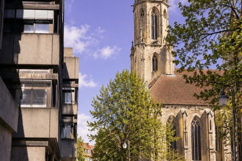 A church with a tall bell tower and a modern building beside it. 4