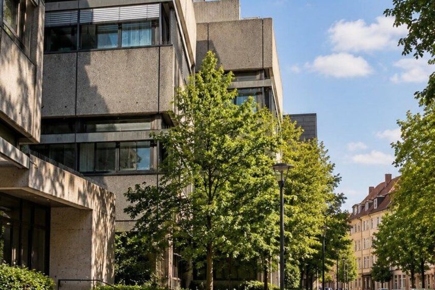 A modern building with large windows and a tree in front. 3