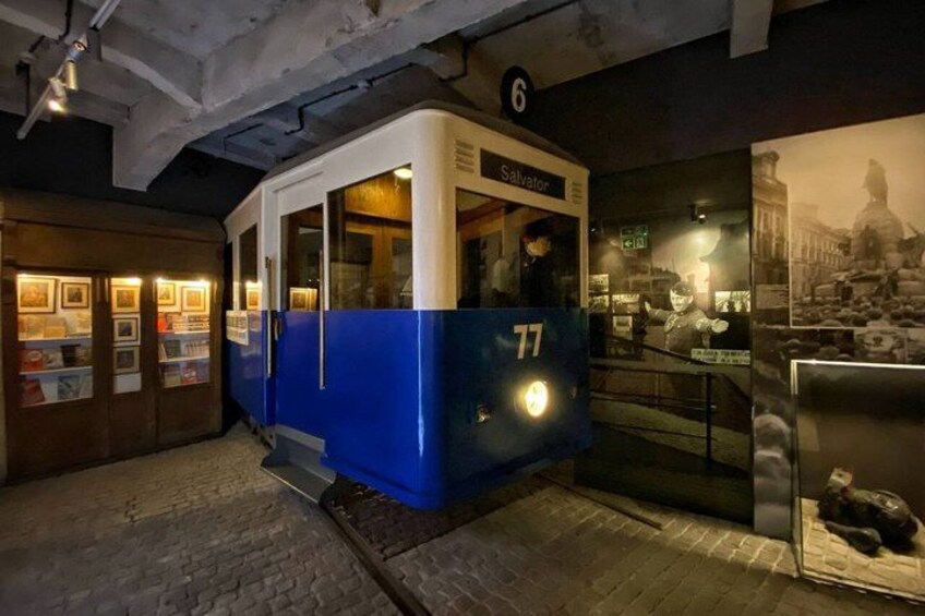 A blue and white tram labeled 'Salvator' with the number 77, inside a museum exhibit. 5