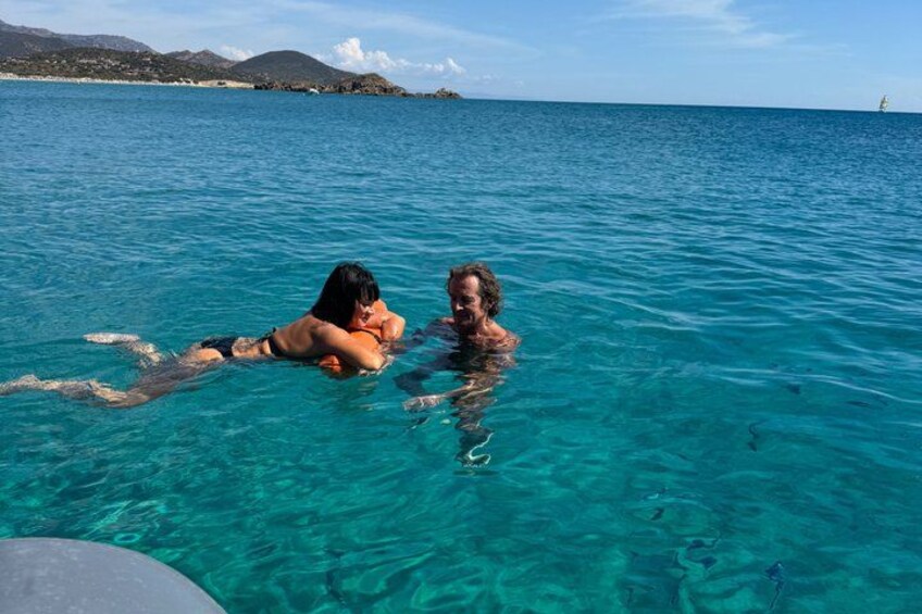 Two people floating in clear blue water with a distant shoreline and mountains. 5