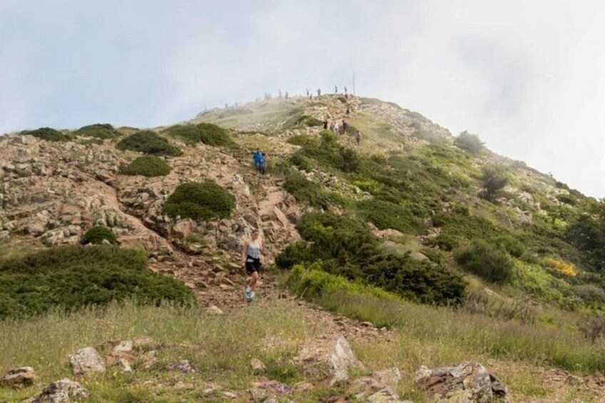 A hiker ascending a rocky hill with sparse vegetation. 1