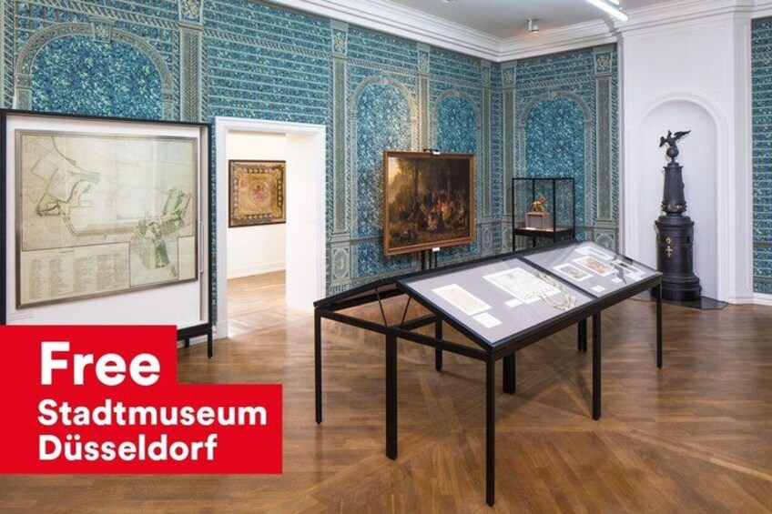 An art exhibition in a museum with blue patterned walls and wooden floors. 2