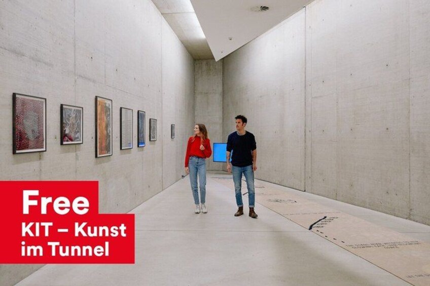 An indoor art gallery with a long corridor and artworks on the walls. 3