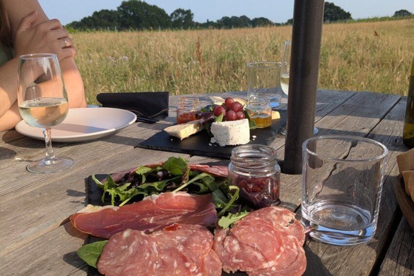 A picnic table with food, wine glasses, and a bottle. 4