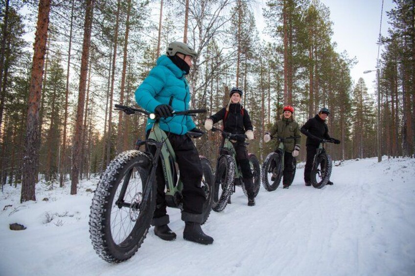 Four people on mountain bikes in a snowy forest. 2