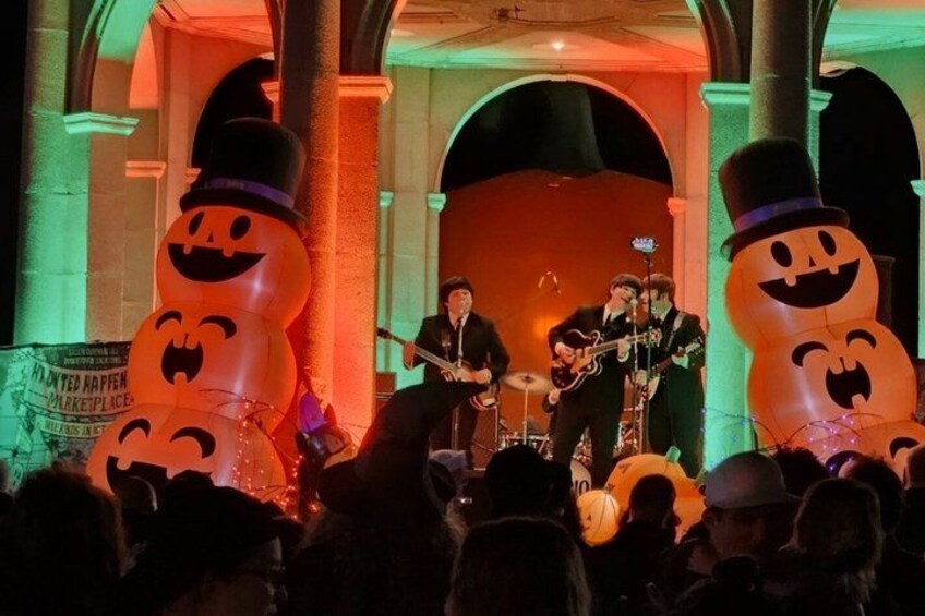 A band performing on a stage with Halloween-themed decorations. 4