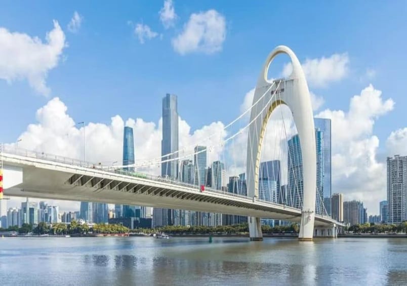 A modern bridge with a distinctive arch design spanning a river, with a city skyline in the background. 1