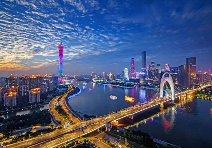 A cityscape at night with illuminated buildings, a river, and a bridge. 3