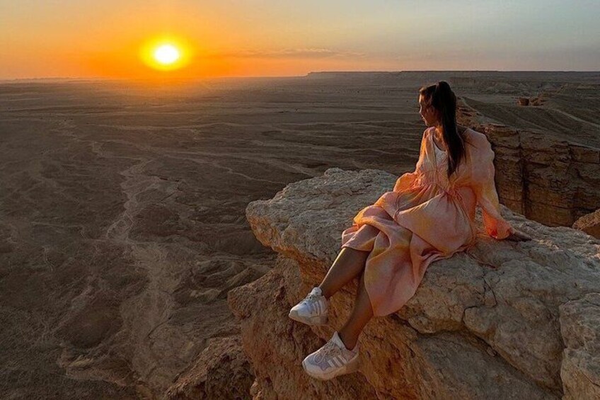 A person sitting on a rock with a sunset in the background. 4