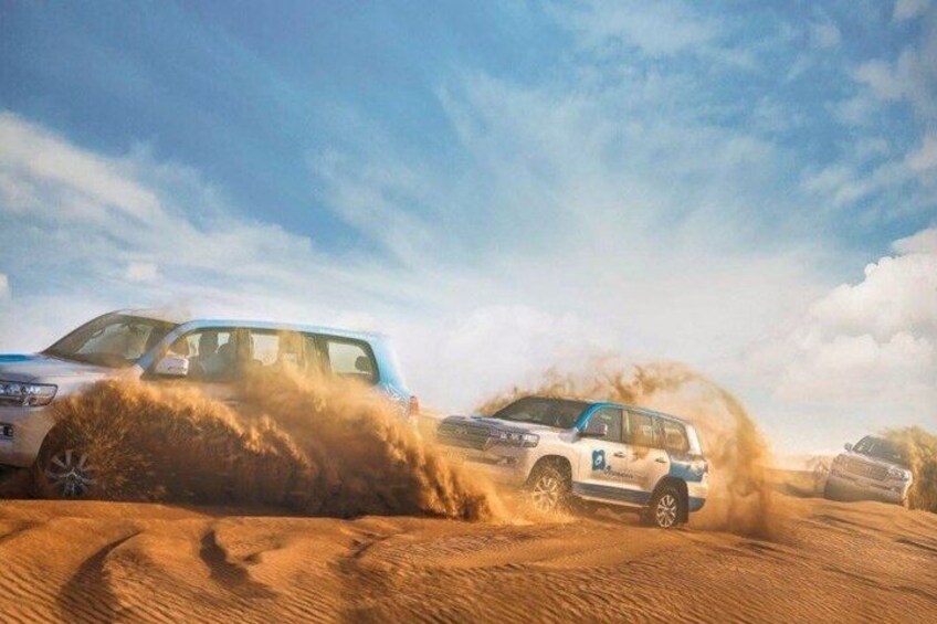 Two vehicles driving through a sandy terrain with dust clouds. 3