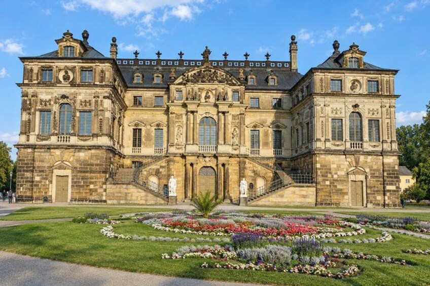 A large, ornate building with a symmetrical facade, a central entrance, and a well-maintained garden with various flowers. 4