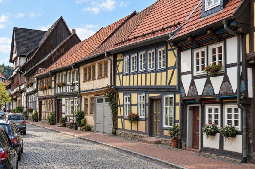 A cobblestone street lined with traditional half-timbered houses, a clear blue sky, and parked cars. 3