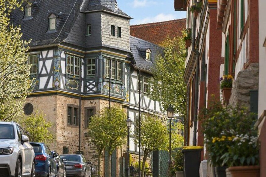 A historic building with a steep gabled roof, a half-timbered facade, and a clock tower. 2