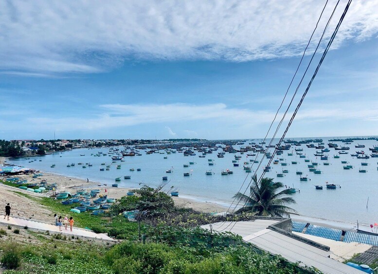 A coastal town with numerous boats docked in the water, a sandy beach, and a clear sky. 2