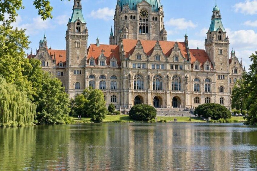 A historic building with a clock tower, surrounded by a lake and greenery. 4