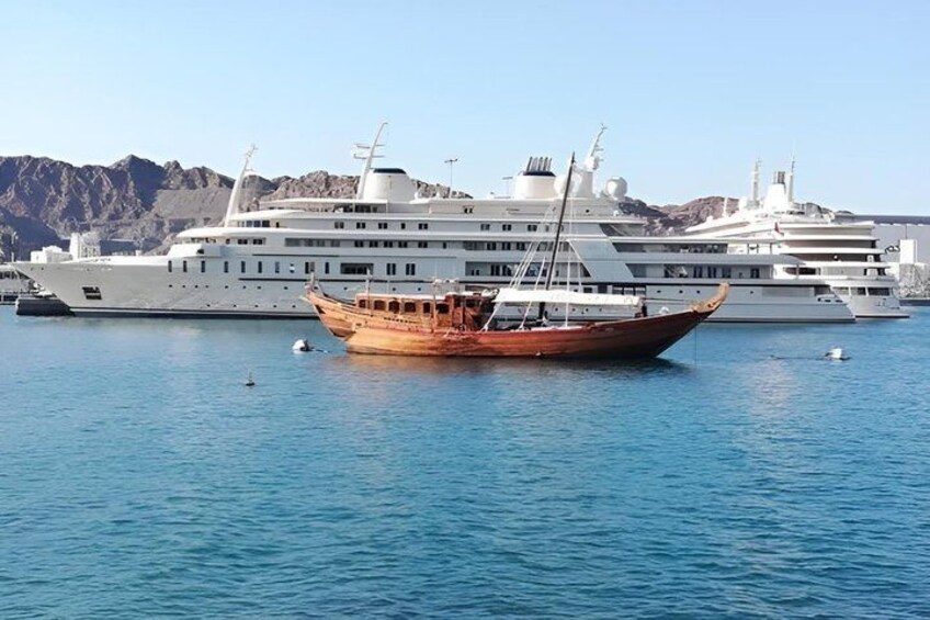 A large cruise ship docked at a marina with a traditional wooden boat in the foreground. 5