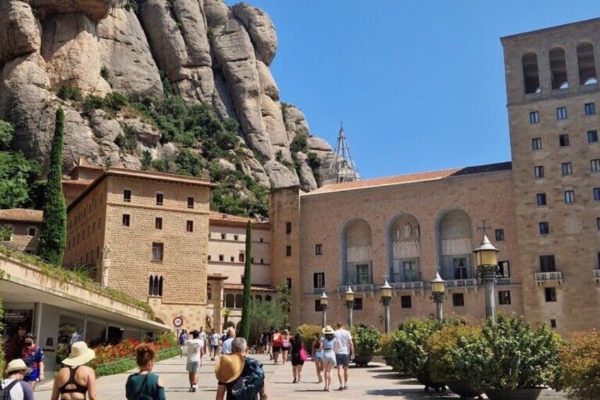 A historic building with arched windows and a large rock formation in the background. 3