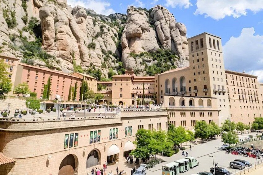 A town with a prominent rock formation, a large building with arches, and a busy street with cars and pedestrians. 4