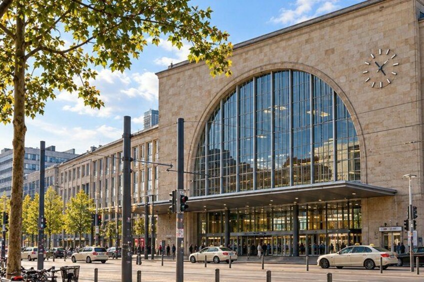A modern building with a large arched glass entrance, a clock on the facade, and a busy street with cars and pedestrians. 4