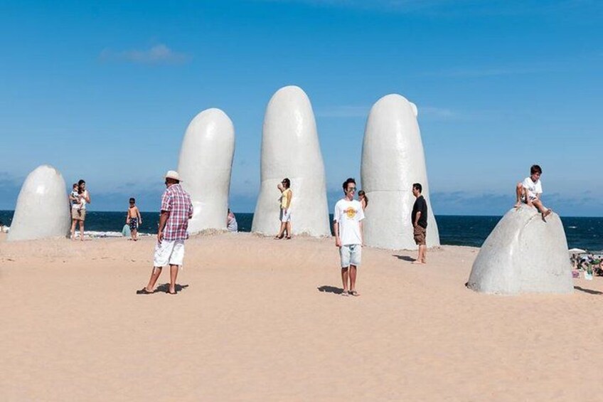 A beach with large white sculptures and people walking around. 2