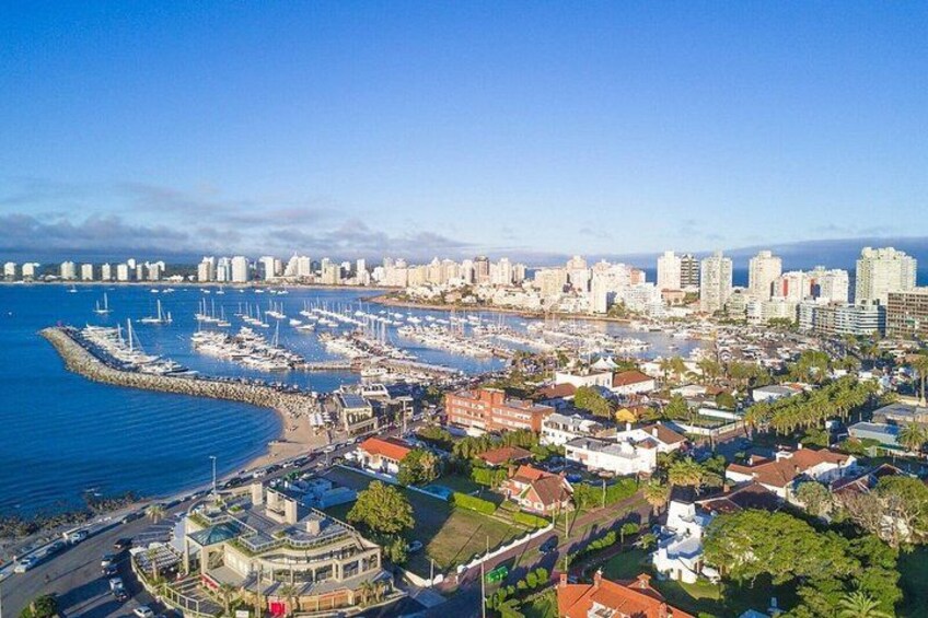 A coastal cityscape with a marina, buildings, and a clear sky. 5