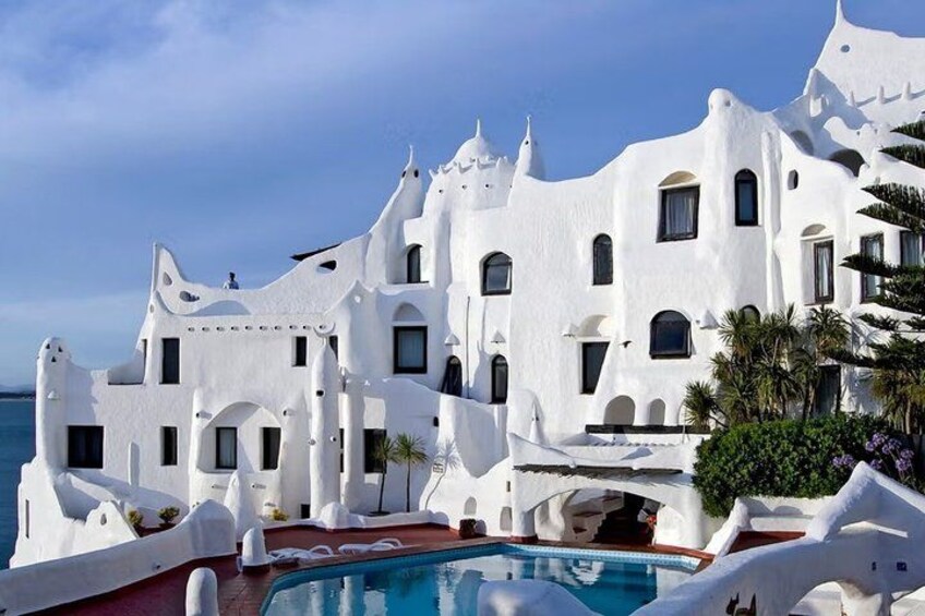 A white building with a pool and palm trees. 1