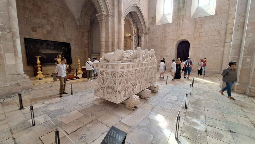 Un sarcófago ornamentado en un museo, con visitantes alrededor. 3