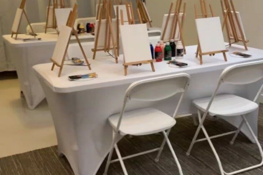 A table with easels and art supplies, likely set up for an art class or workshop. 2