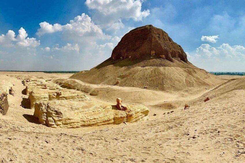 A large mound with a flat top, surrounded by sand dunes and sparse vegetation. 3