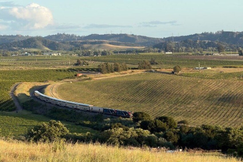 A train traveling through a rural landscape with fields and hills. 3