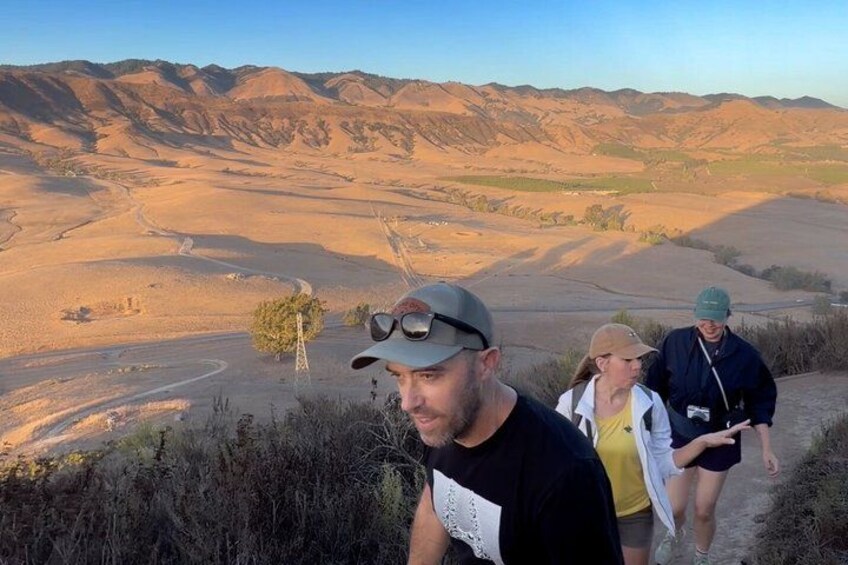 A group of people hiking on a trail with a desert landscape in the background. 5