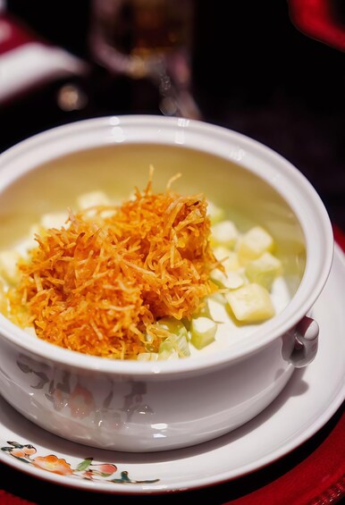 Un bol de soupe contenant des carottes râpées et des légumes coupés en dés, servi sur une assiette blanche. 2