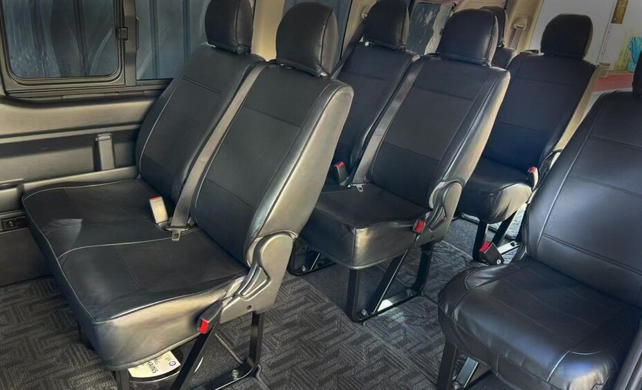 Sillas de cuero negro en línea, con reposacabezas y cinturones de seguridad, dentro de un vehículo. 4