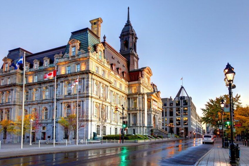 A historic building with a clock tower, a river, and a street with cars and a pedestrian crossing. 2