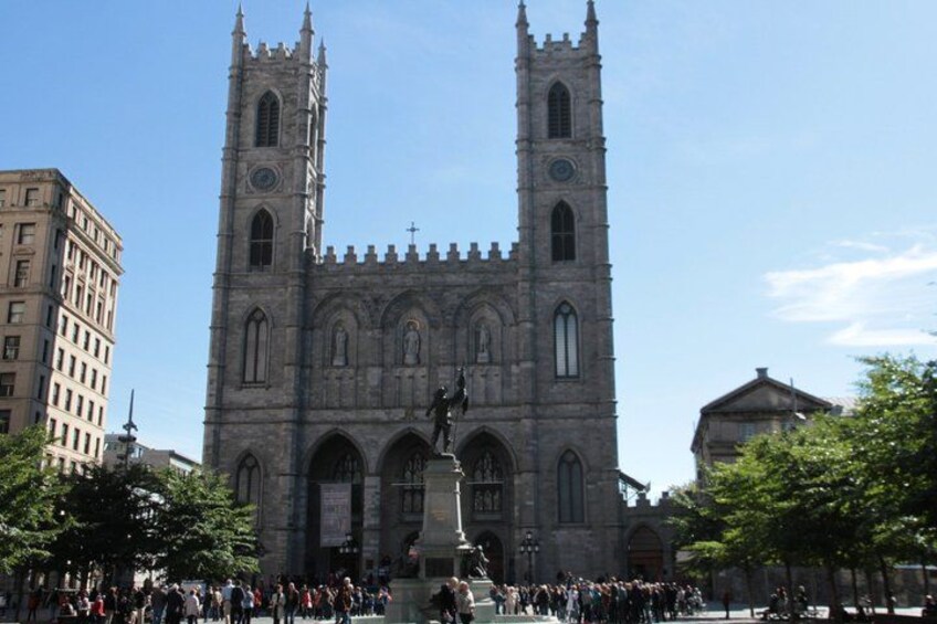 A historic cathedral with two towers and a statue in front. 4