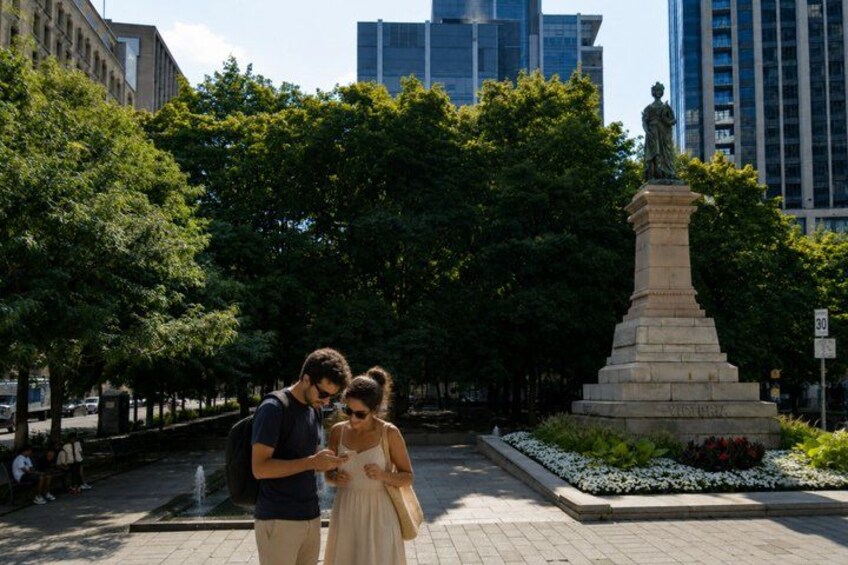 A couple standing in a park with a statue in the background. 5